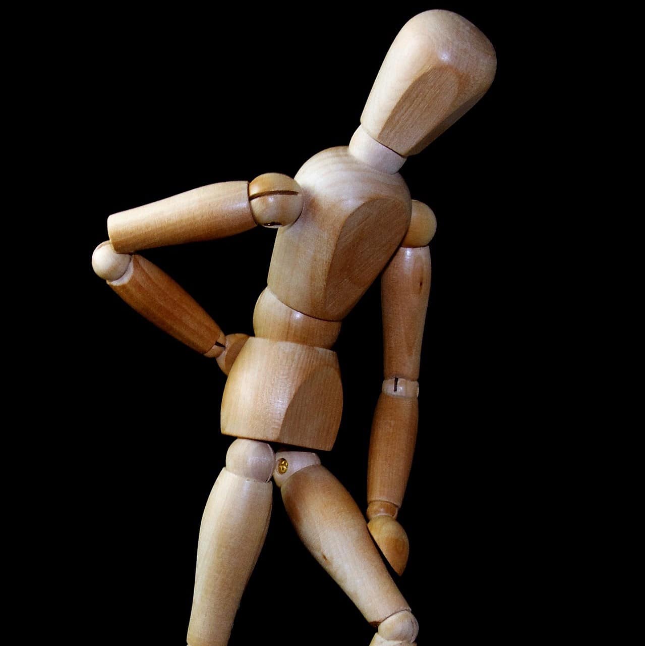 A man made of wood standing with back pain