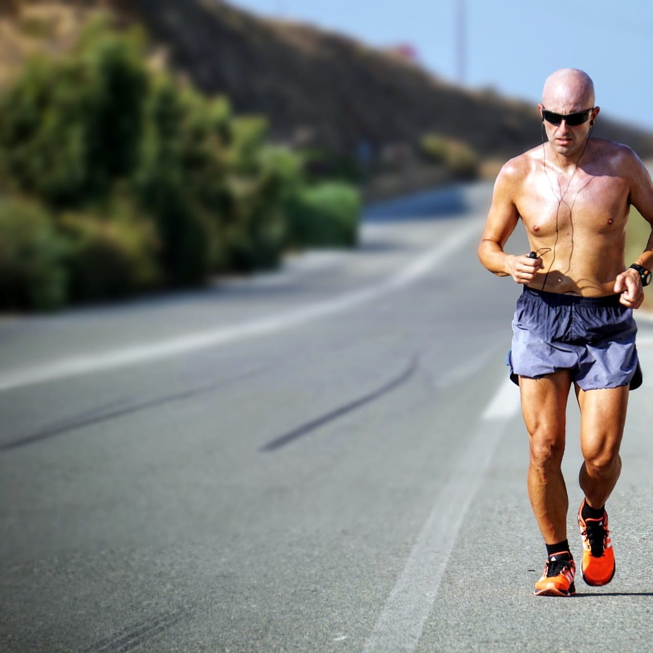 Man running on a road without a shirt
