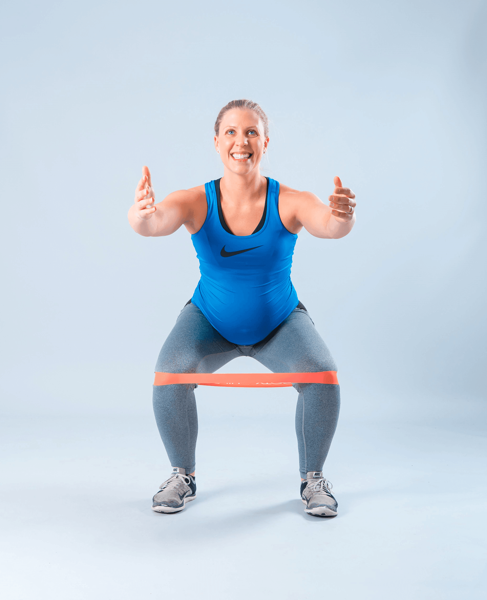 Pregnant women in blue using bands to workouts