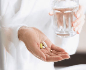 A woman holding pills and water